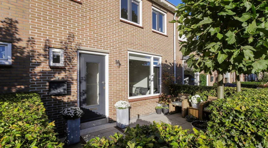 Een bakstenen huis met struiken ervoor. verkoopstyling schiedam, neutrale inrichting, woningfotografie
