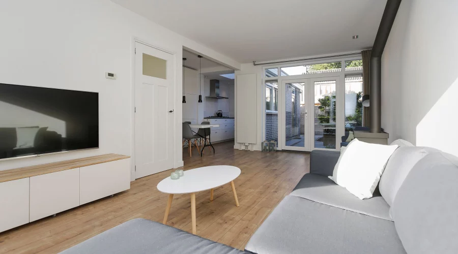 Een woonkamer met een witte bank en tv. verkoopstyling schiedam, neutrale inrichting, woningfotografie