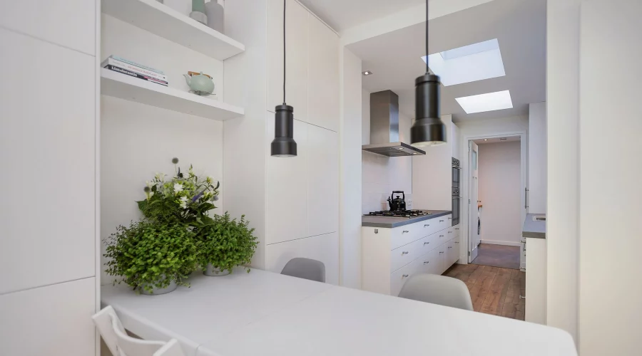 Een witte keuken met een tafel en stoelen. verkoopstyling schiedam, neutrale inrichting, woningfotografie