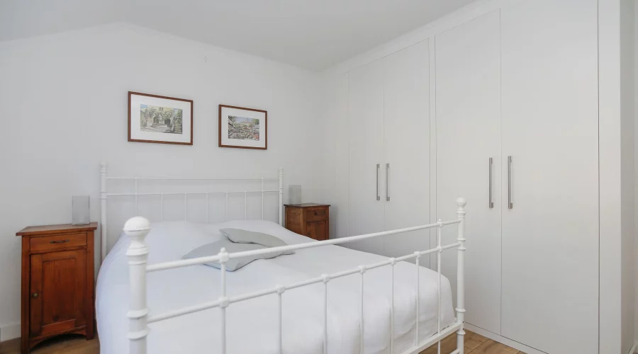 Een slaapkamer met een wit bed en witte kasten. verkoopstyling schiedam, neutrale inrichting, woningfotografie
