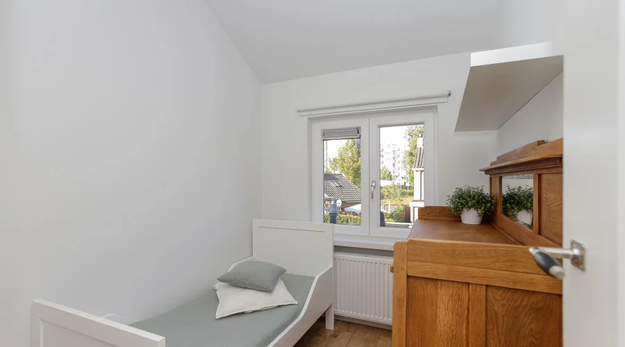 Een kleine slaapkamer met een bed en een dressoir. verkoopstyling schiedam, neutrale inrichting, woningfotografie