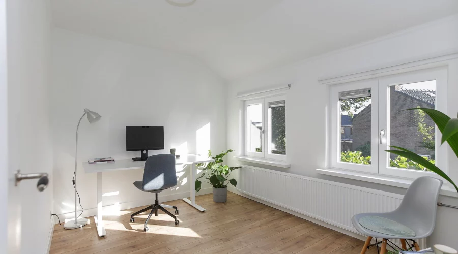 Een kamer met een bureau, stoel en raam. verkoopstyling schiedam, neutrale inrichting, woningfotografie